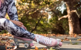 Persona ajustándose unos patines en un parque, preparándose para patinar al aire libre en un entorno natural.