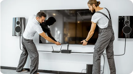 imagen de dos técnicos instalando un televisor y un equipo de sonido en la pared