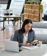 imagen de una mujer mirando el movil y tomando notas en la mesa de una oficina
