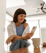 imagen chica joven mirando el movil con una taza de cafe en la mesa